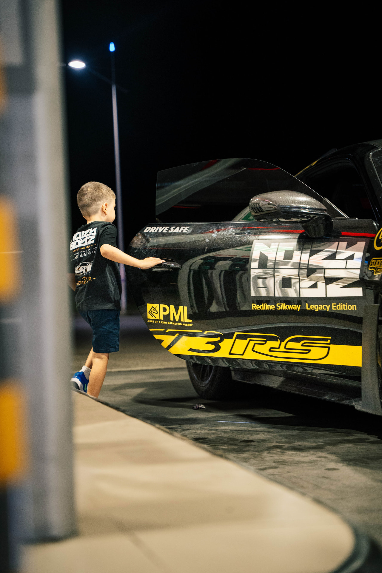 A young guest reaching into the Noizy Boyz GT3 RS at night