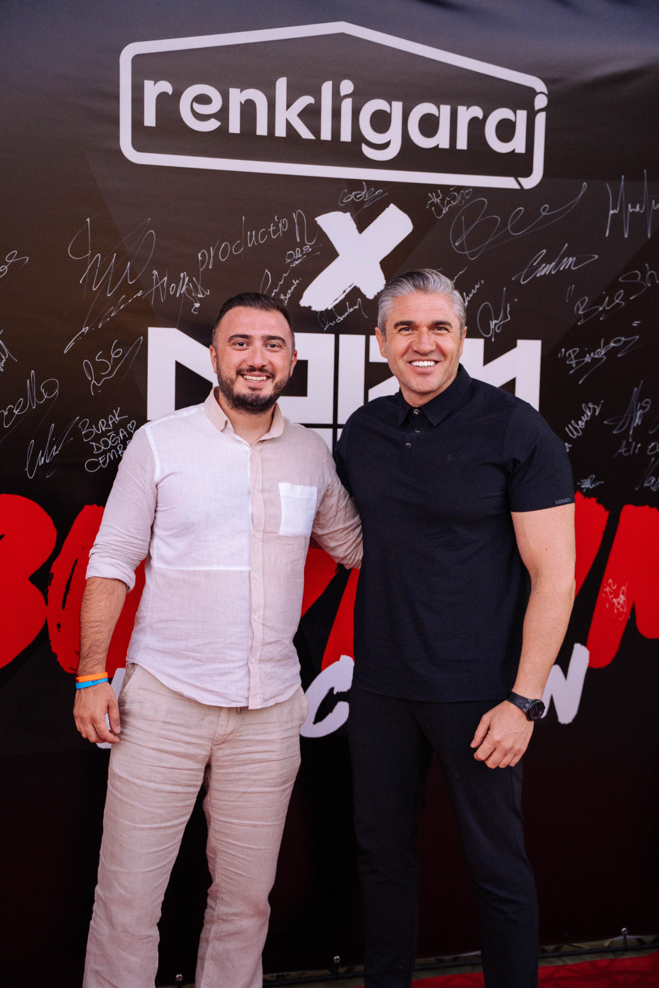 Two members posing in front of a signed event backdrop