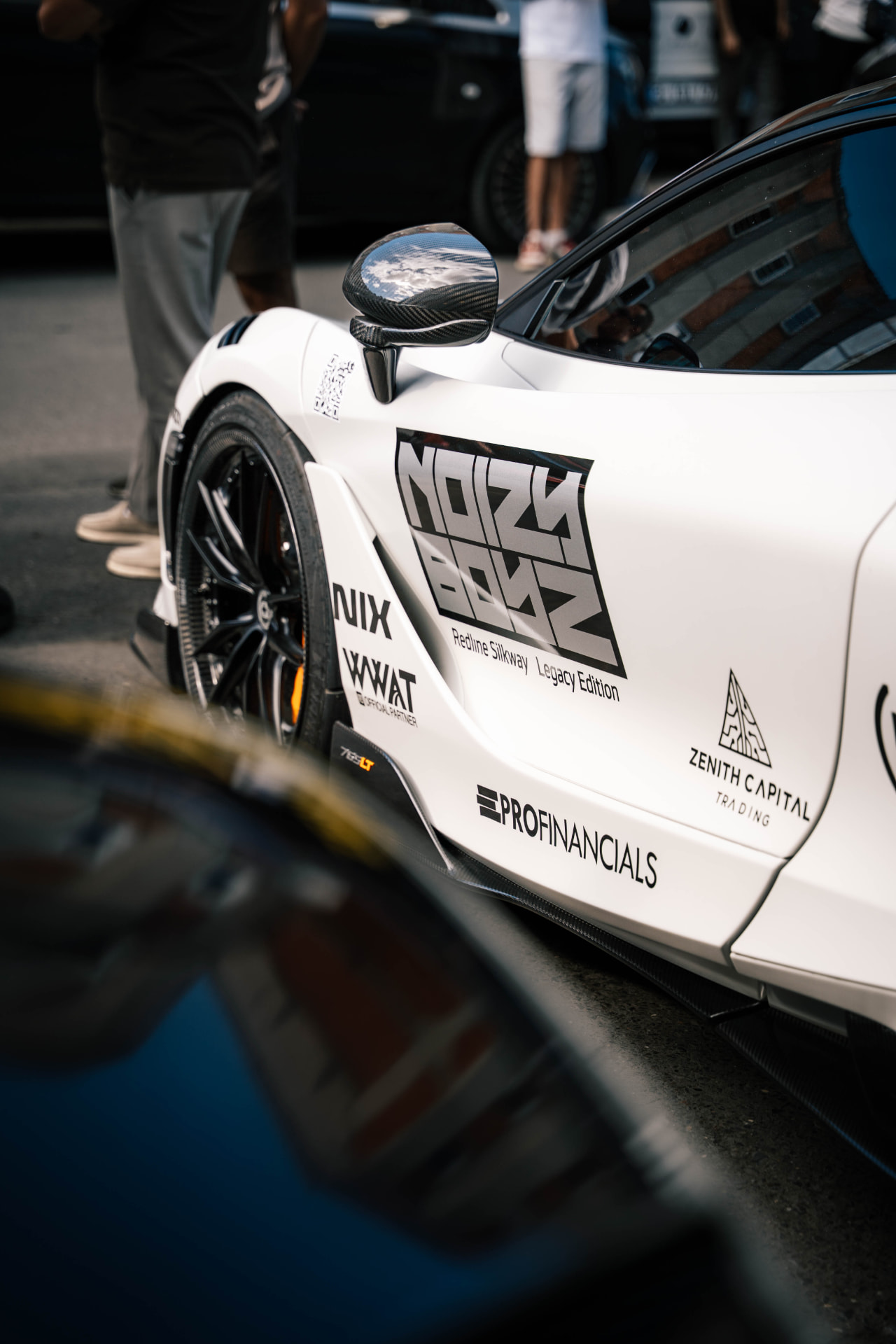 Side of a white McLaren carrying the Noizy Boyz and sponsor graphics